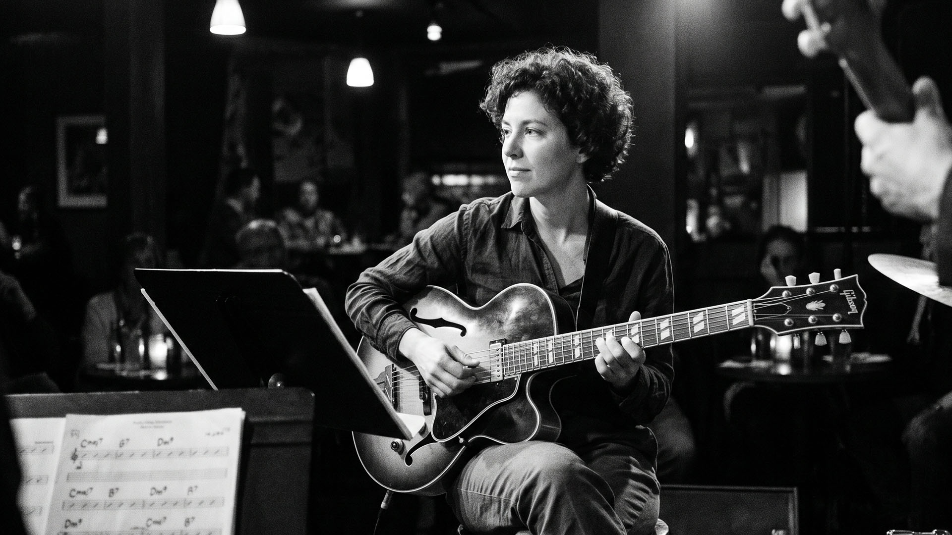 Black-and-white candid of a jazz guitarist performing in a small room