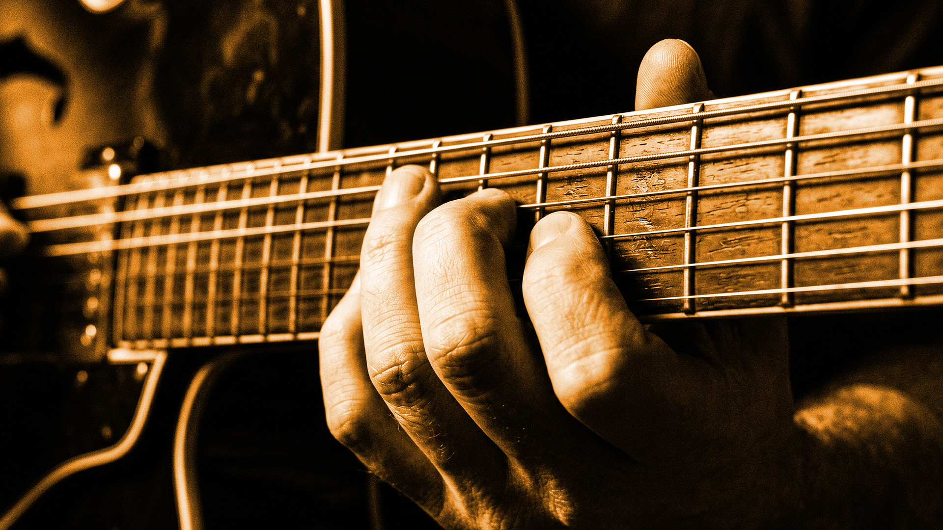 Close-up of a hand fretting a jazz chord high on a guitar neck