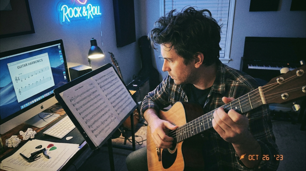 guitar player studying natural harmonics